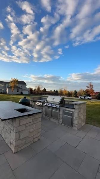 Stone outdoor kitchen and bar on a large paver patio